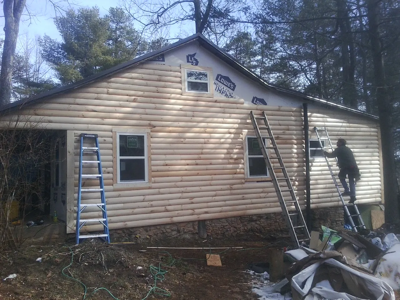 Ladders set against fresh log siding during an exterior remodel in Fort George G Meade
