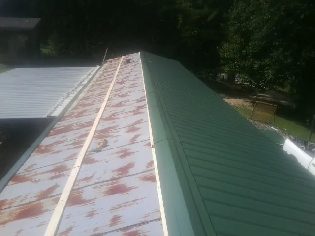 Old rusted panels beside newly installed green metal roofing — Wind Damage Roof Repair by Roofing Brothers in Fort George G Meade