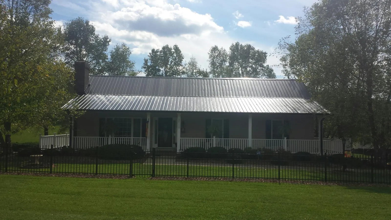 Gray metal roof on a brick ranch with a full width front porch — Gutter Guard Installation work by our crew in Fort George G Meade