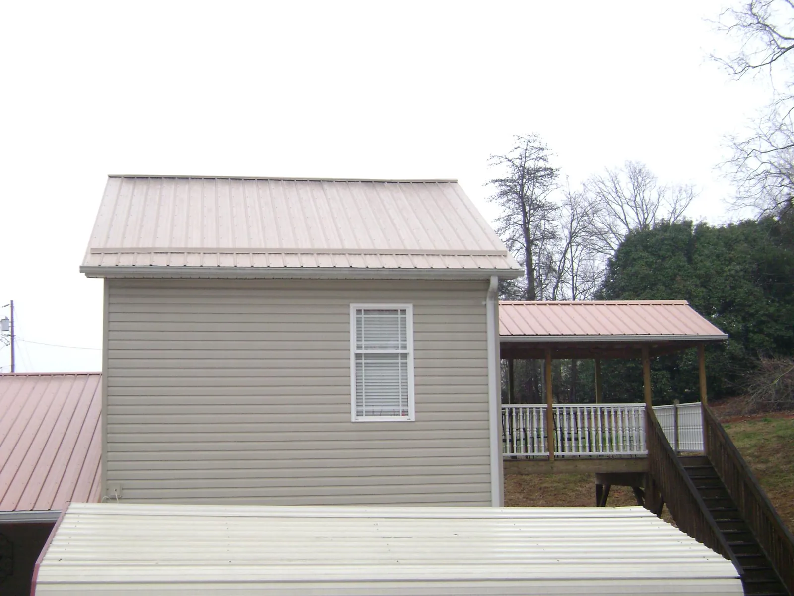 Tan metal roofs on a two story addition and attached porch, from a Roof Replacement job in Fort George G Meade