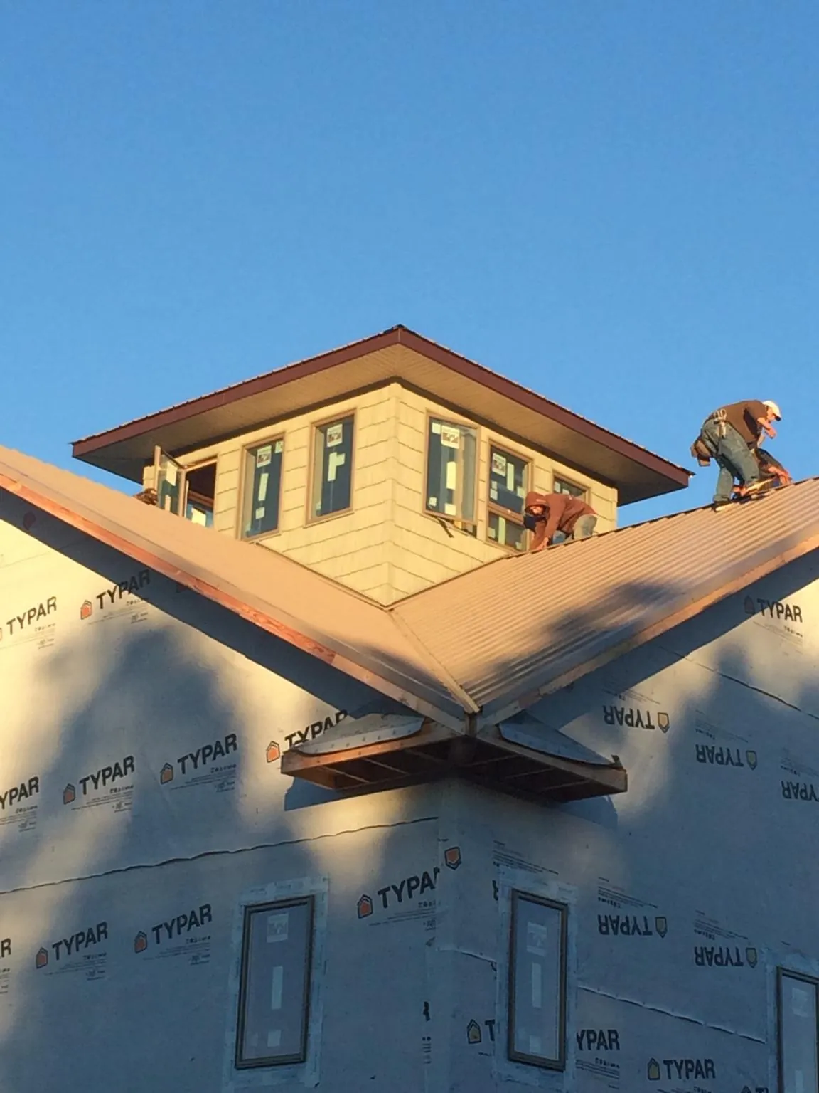 Roofers working around a rooftop cupola on a new metal roof at sunset — Roof Waterproofing in Fort George G Meade by Roofing Brothers